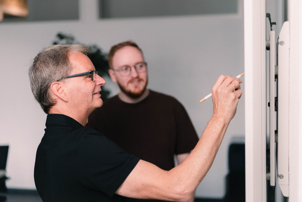 zwei maenner stehen an whiteboard